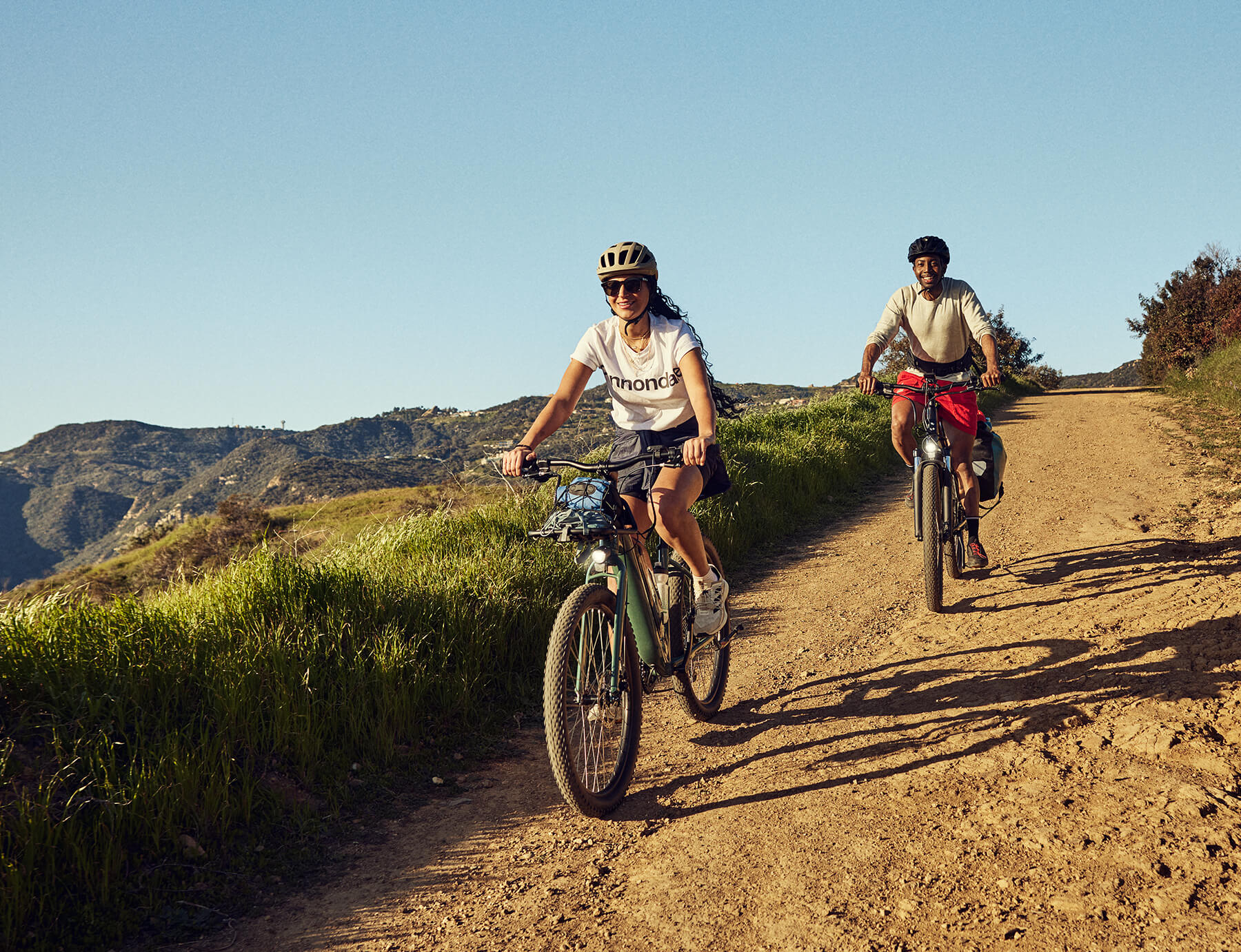 two people riding bikes on a dirt road
